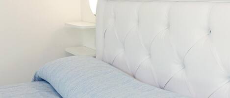 A neatly made bed with a white headboard and a blue blanket.
