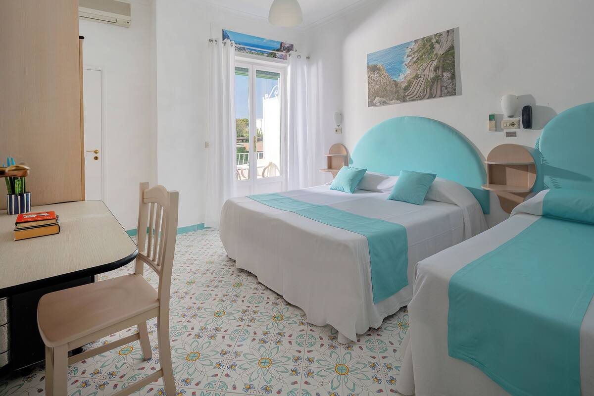 A bedroom with two beds, a desk, and a chair.