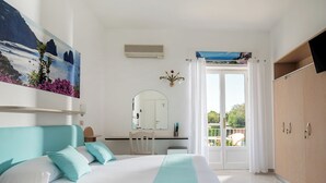 Um quarto com cama, escrivaninha, cadeira, espelho e guarda-roupa.