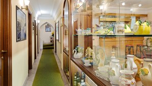 Um corredor com carpete verde, portas de madeira e uma vitrine de vidro com peças de cerâmica.