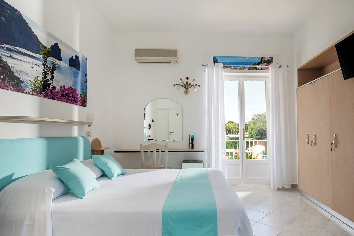 Un dormitorio con cama, escritorio, silla, espejo y armario.