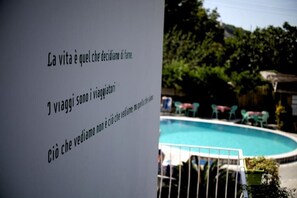 A poolside view with a sign in Italian.