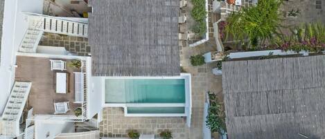 A modern hotel with a rooftop pool, multiple balconies, and outdoor seating areas.