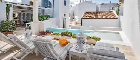 Una piscina al aire libre, sillones reclinables de piscina