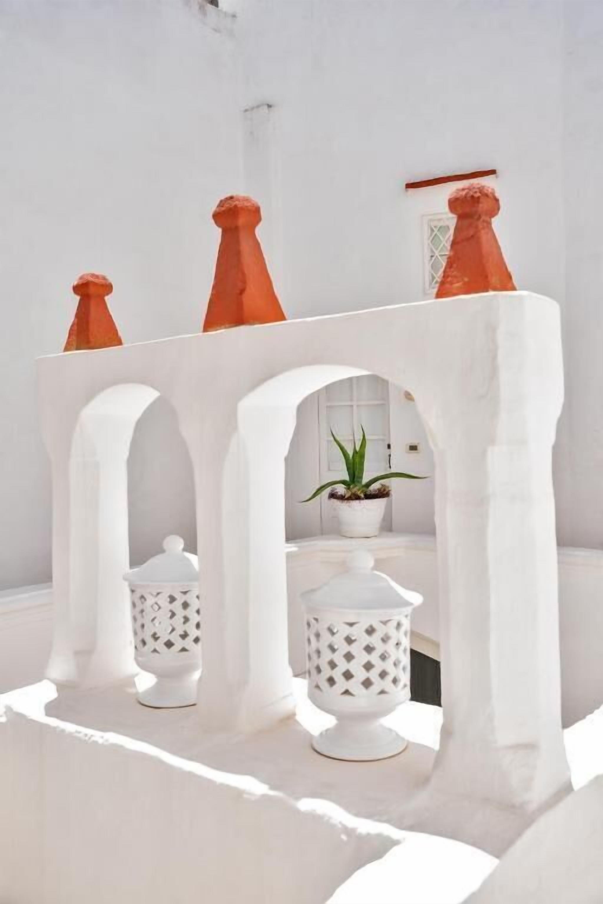 Una estructura arquitectónica blanca con arcos y una planta en maceta.