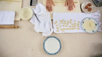 A kitchen with a rolling pin, a bowl of flour, a plate of dough balls, and a rolling pin on a countertop.