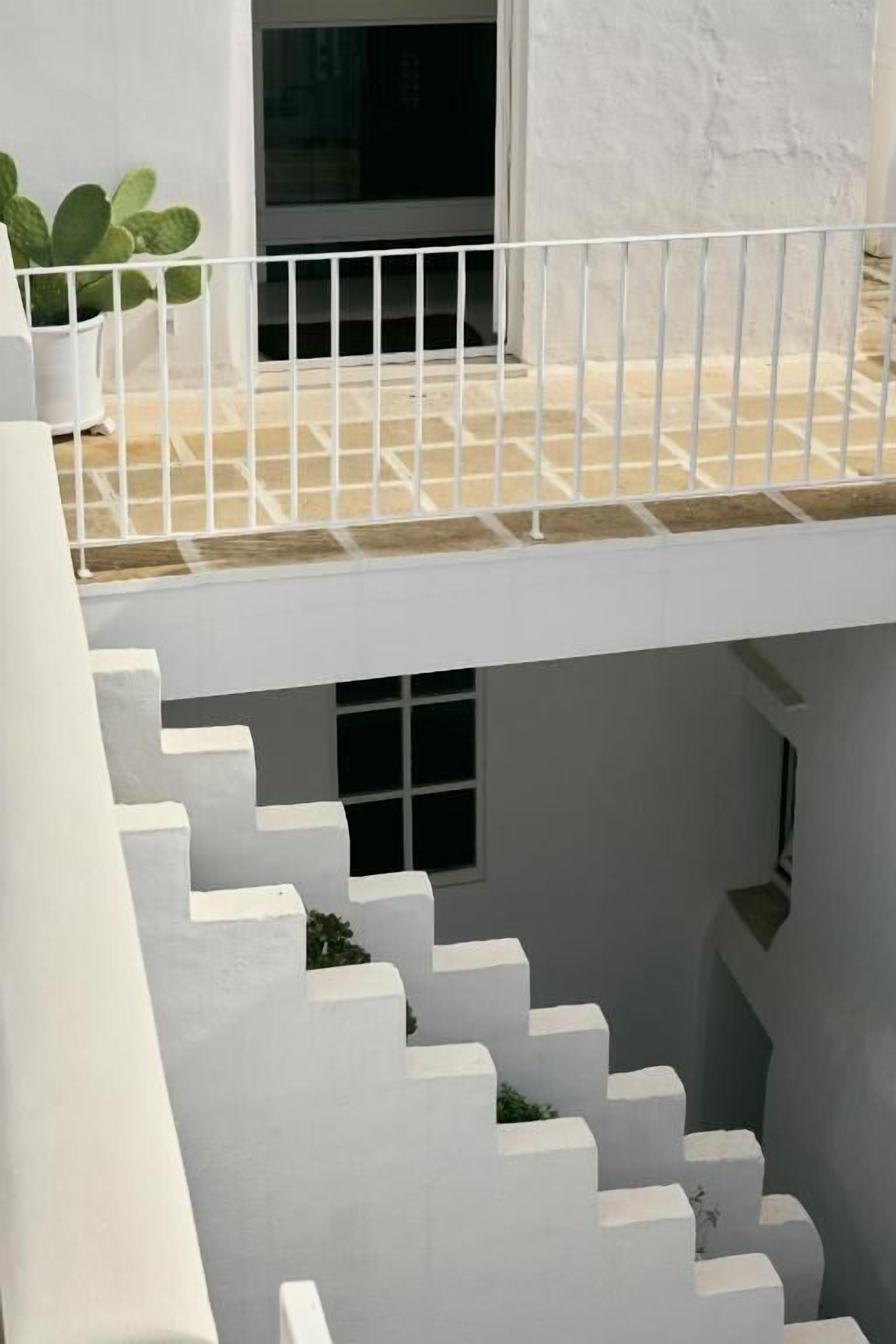 A white staircase leading to a balcony with a potted plant.
