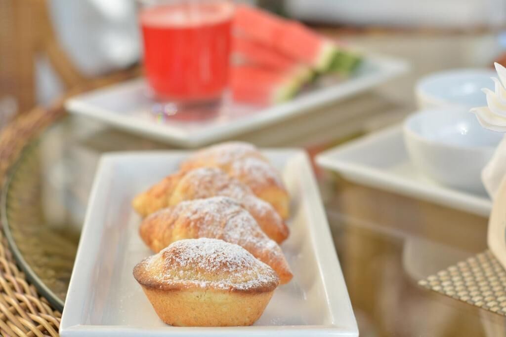 A tray of muffins on a white plate, a red cup, and a slice of watermelon on a table.