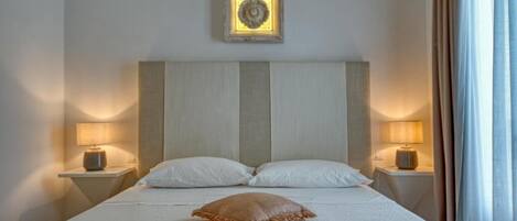 A neatly made bed with two pillows, a single decorative pillow, and two bedside lamps on either side.