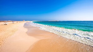 A beach with a clear sky, sandy shore, and a few beach chairs. - JAZ Almaza Beach Resort, Almaza Bay (Marsa Matrouh)