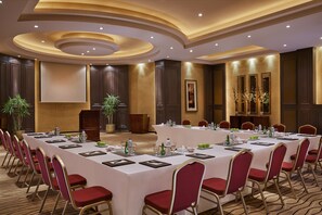A conference room with a long table, red chairs, and a podium.