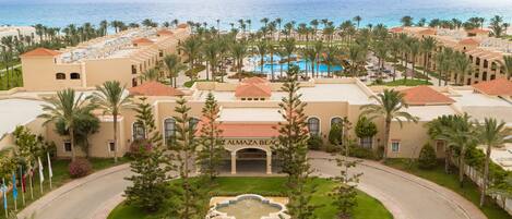 A resort with multiple buildings, a central pool, and a view of the ocean.