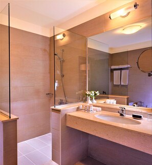A modern bathroom with a glass shower enclosure, a large mirror, and a vanity with a sink and towel rack.