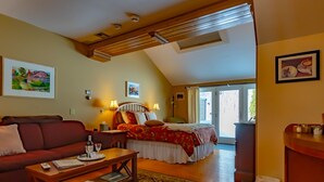 A cozy room with a bed, a sofa, a small table, and a desk. There are two lamps on the bed and a window with curtains. - Shaker Mill Inn (West Stockbridge)
