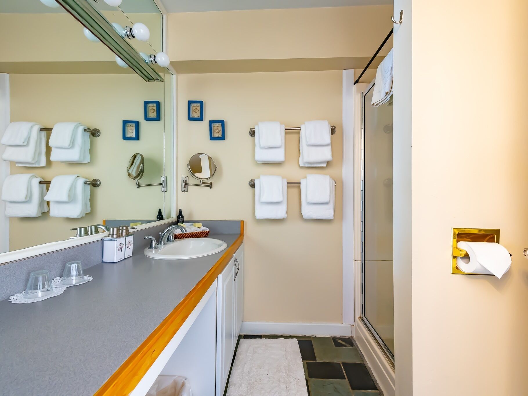 Une salle de bain équipée d’un lavabo, d’un miroir et de plusieurs porte-serviettes.