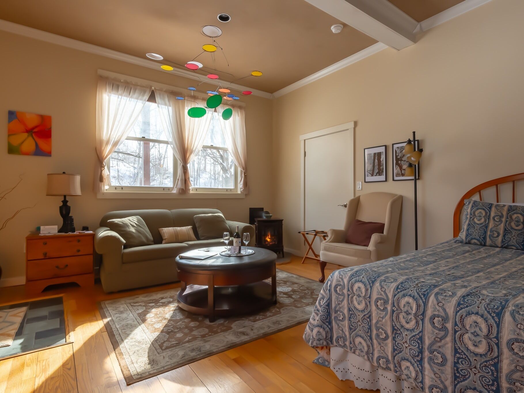 A cozy bedroom with a bed, a sofa, a coffee table, and a fireplace.