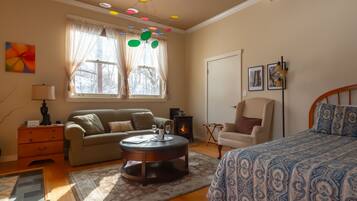 A cozy bedroom with a bed, a sofa, a coffee table, and a fireplace.