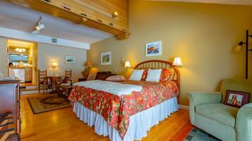 A bedroom with a wooden bed, a desk with a chair, a sofa, and a small table with a lamp.