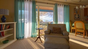 A cozy living room with a sofa, a small table, and a bookshelf. There is a window with curtains, and a painting on the wall. - Shaker Mill Inn (West Stockbridge)