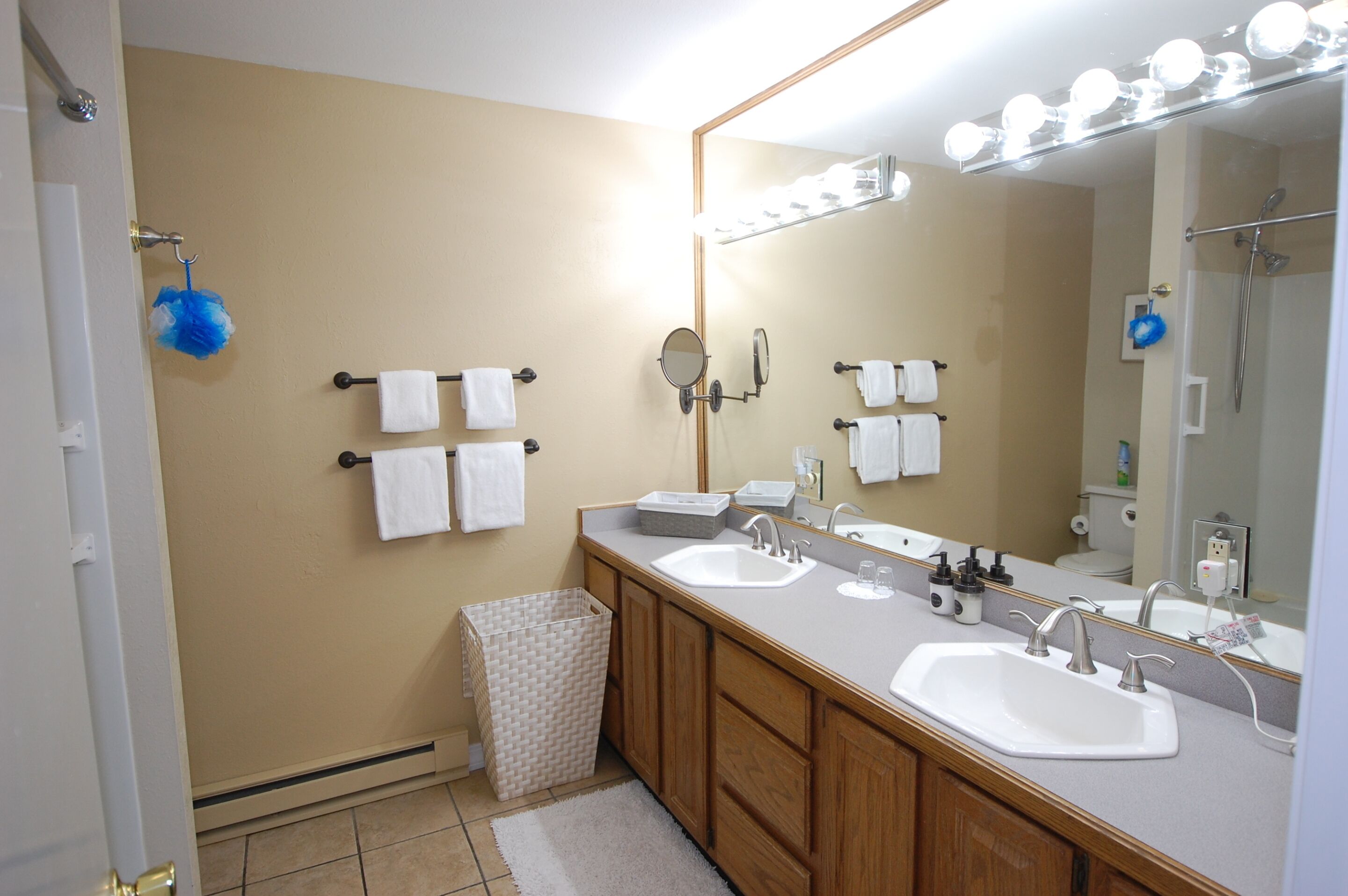 A bathroom with two sinks, a large mirror, and towel racks.