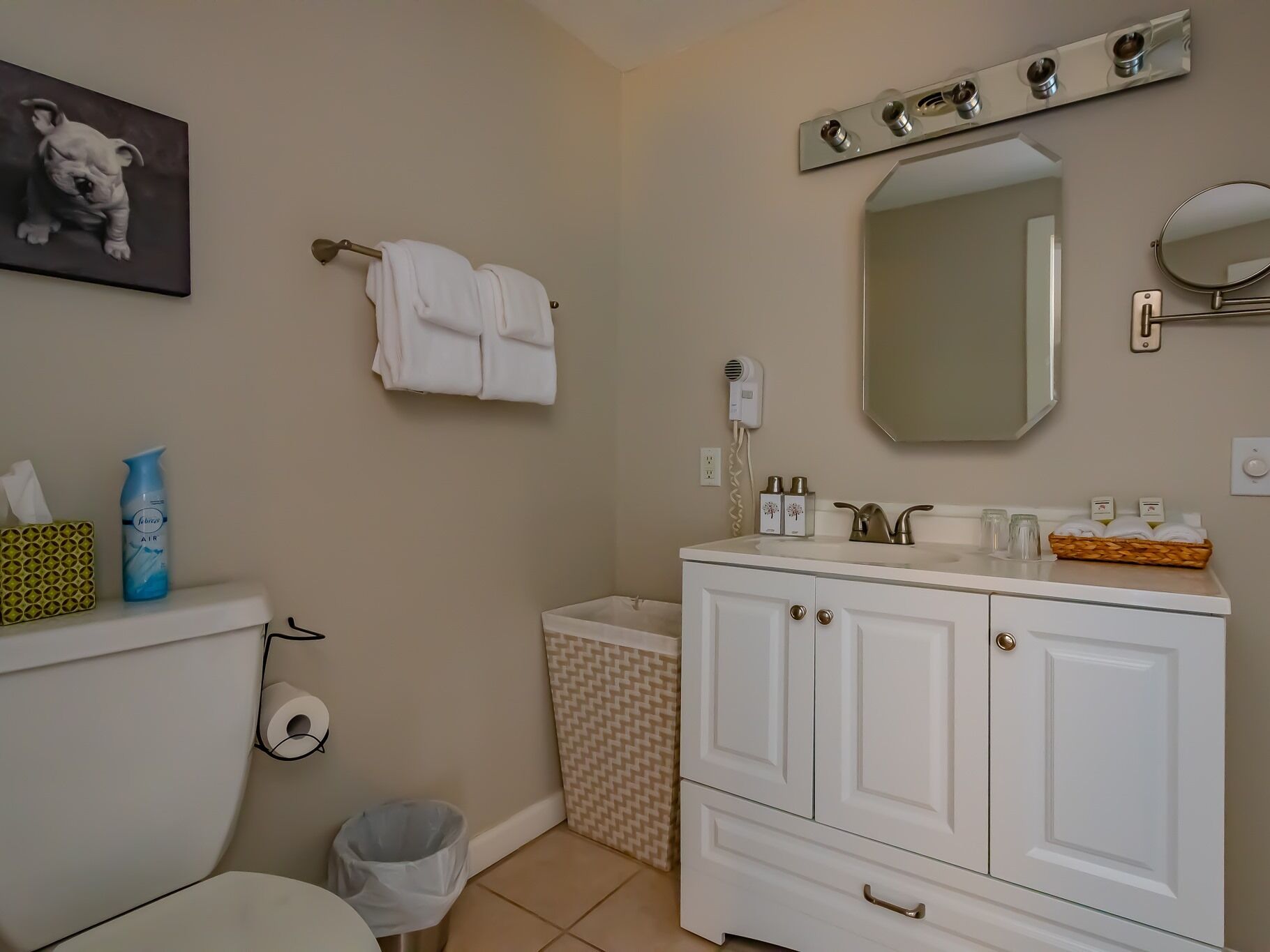 Une salle de bain équipée d’un WC, d’un lavabo, d’un meuble-vasque, d’un porte-serviettes et d’une poubelle.