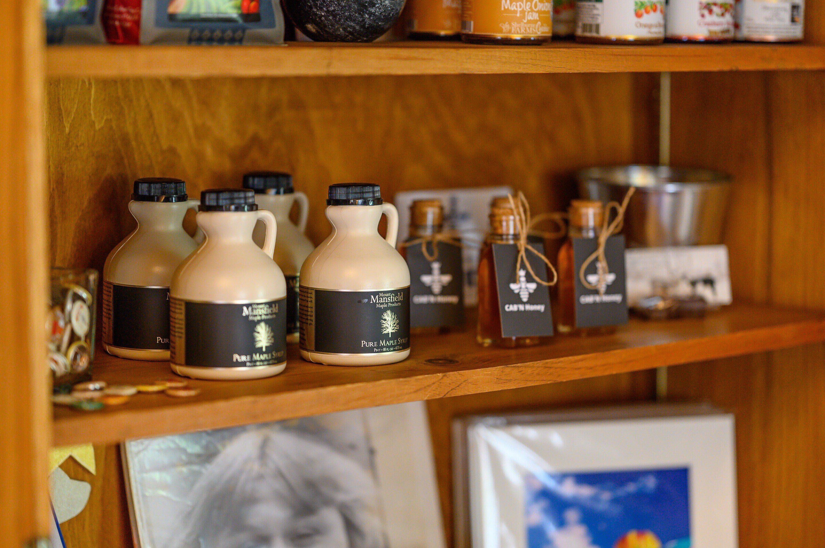 A shelf with various bottles and containers, including a few with labels that read "Pure Maple Syrup."