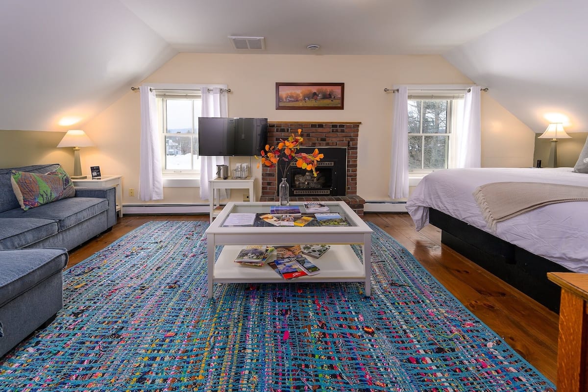 A cozy bedroom with a fireplace, a television, and a colorful rug.