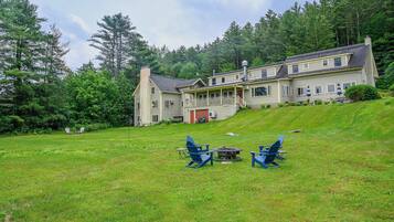 A large house with a porch, a fire pit, and outdoor seating.