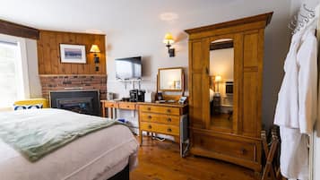 Ein Hotelzimmer mit Bett, Holzschrank, Schreibtisch mit Fernseher und Spiegel.