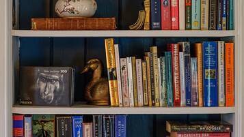 A bookshelf with various books, a decorative vase, and a golden duck figurine.
