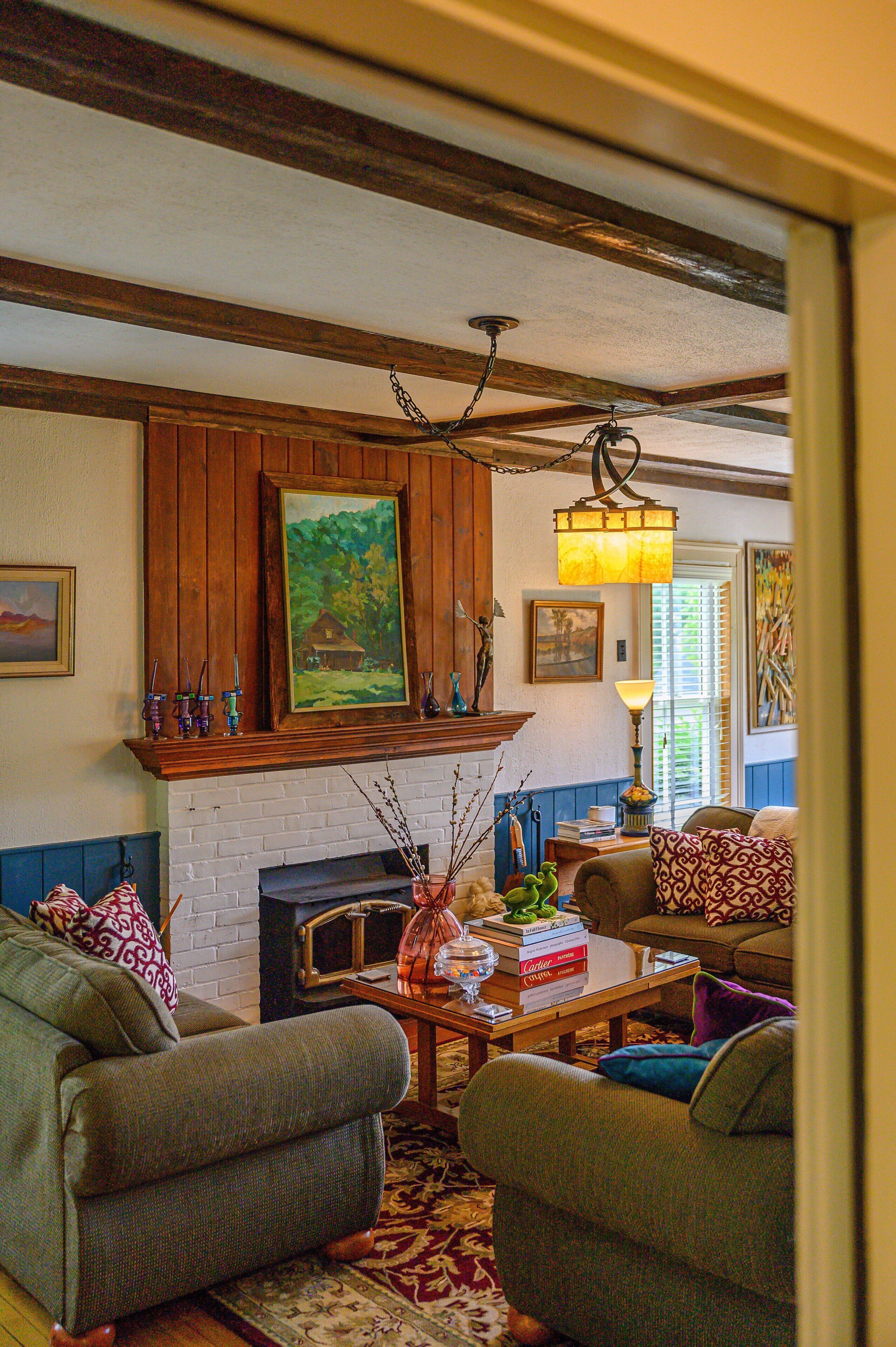 A cozy living room with a fireplace, wooden beams, and a comfortable seating area.