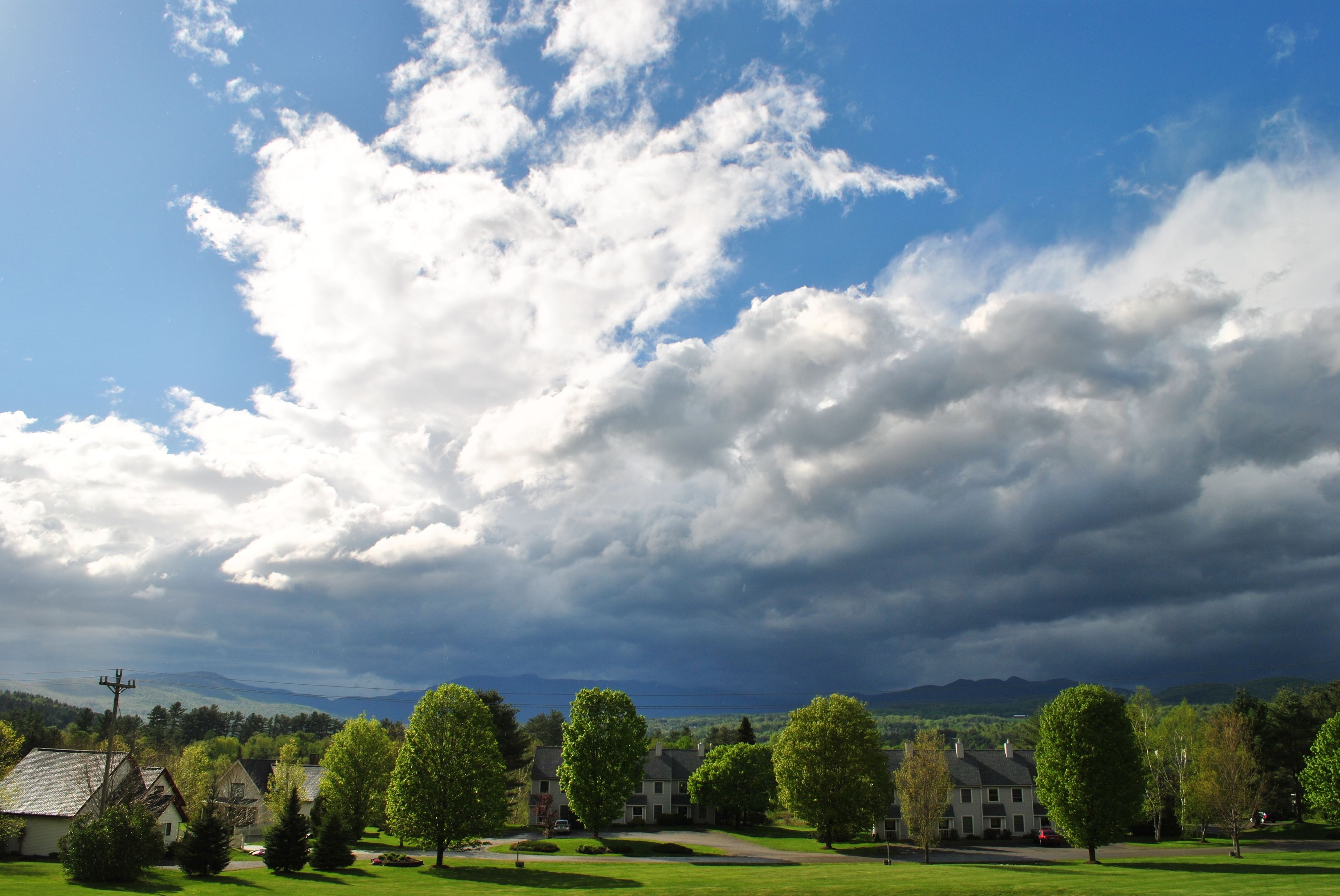 A residential area with houses, a well-maintained lawn, and a clear sky with clouds.