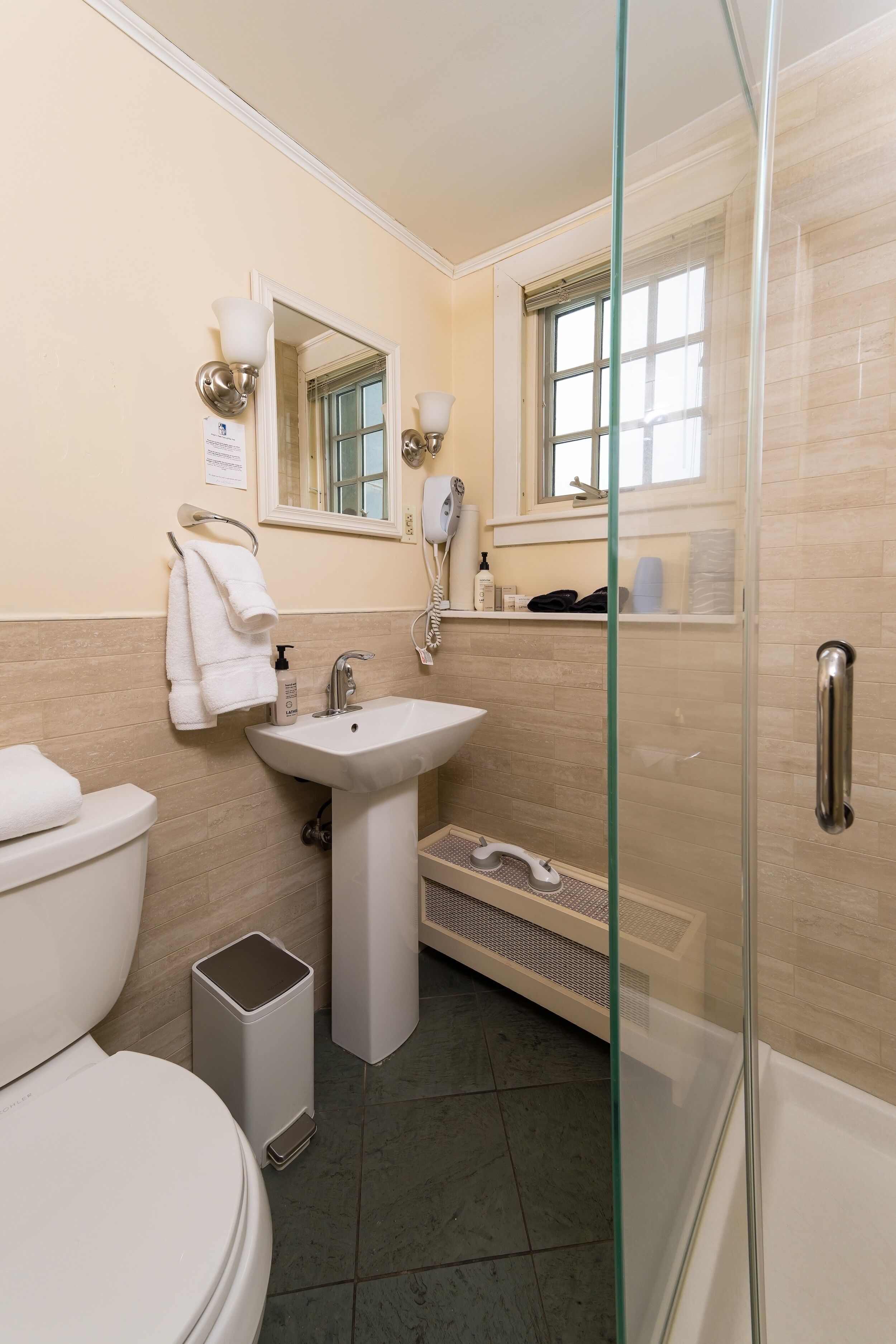 Une salle de bain moderne équipée de toilettes, d’un lavabo et d’une douche à parois de verre.
