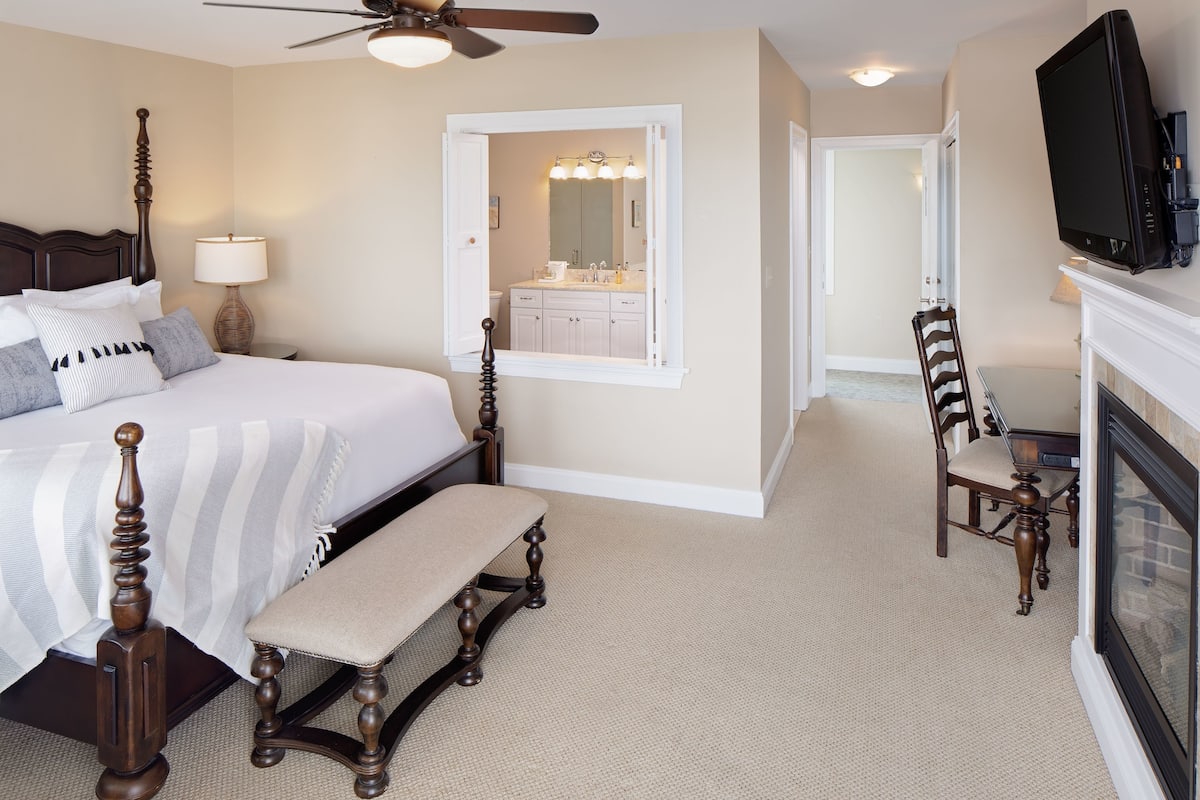A bedroom with a bed, bedside table, lamp, and a television.