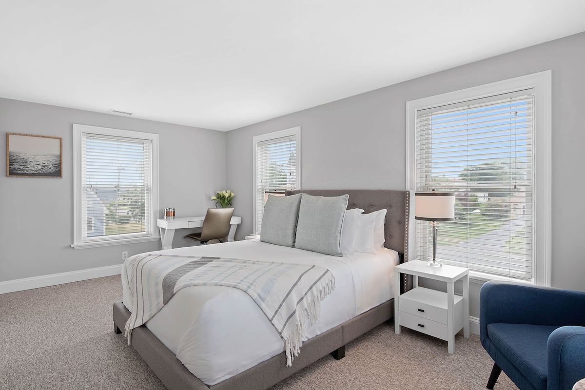 A bedroom with a large bed, bedside tables, a desk, and a chair.