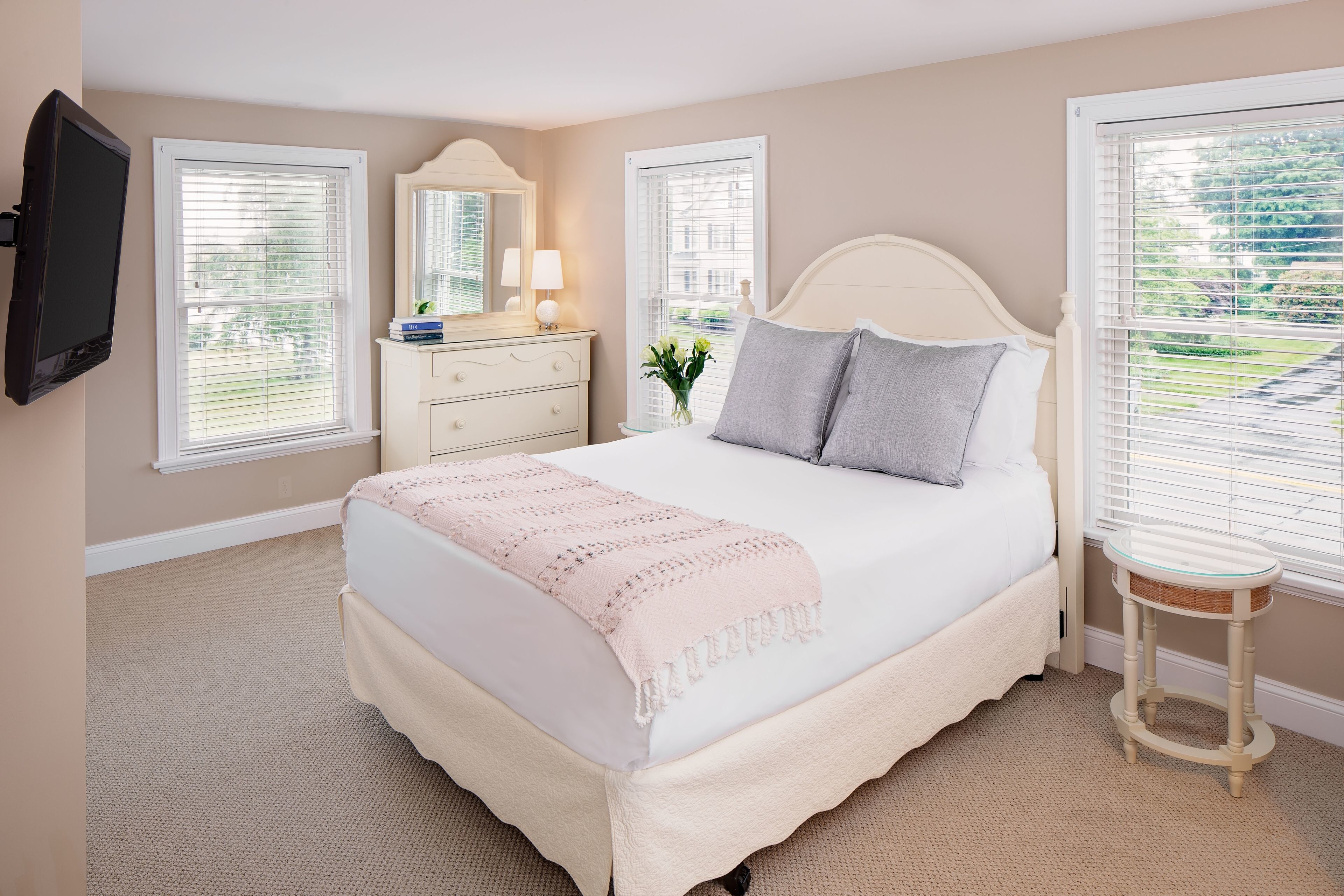 Un dormitorio con cama, cómoda, espejo y una mesita.