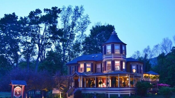 A large, multi-story house with a prominent tower, surrounded by a well-maintained lawn and trees. - Fairlawn Inn (Hunter)