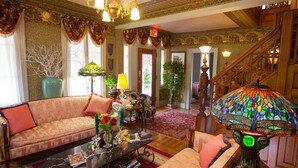 A richly decorated living room with a sofa, a coffee table, and a colorful stained glass lamp. - Fairlawn Inn (Hunter)
