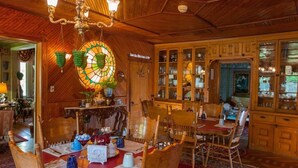 A dining area with wooden furniture, a stained glass window, and a cabinet with glass doors. - Fairlawn Inn (Hunter)