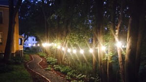 A pathway lined with trees and illuminated string lights, leading to a building with a visible entrance. - Fairlawn Inn (Hunter)