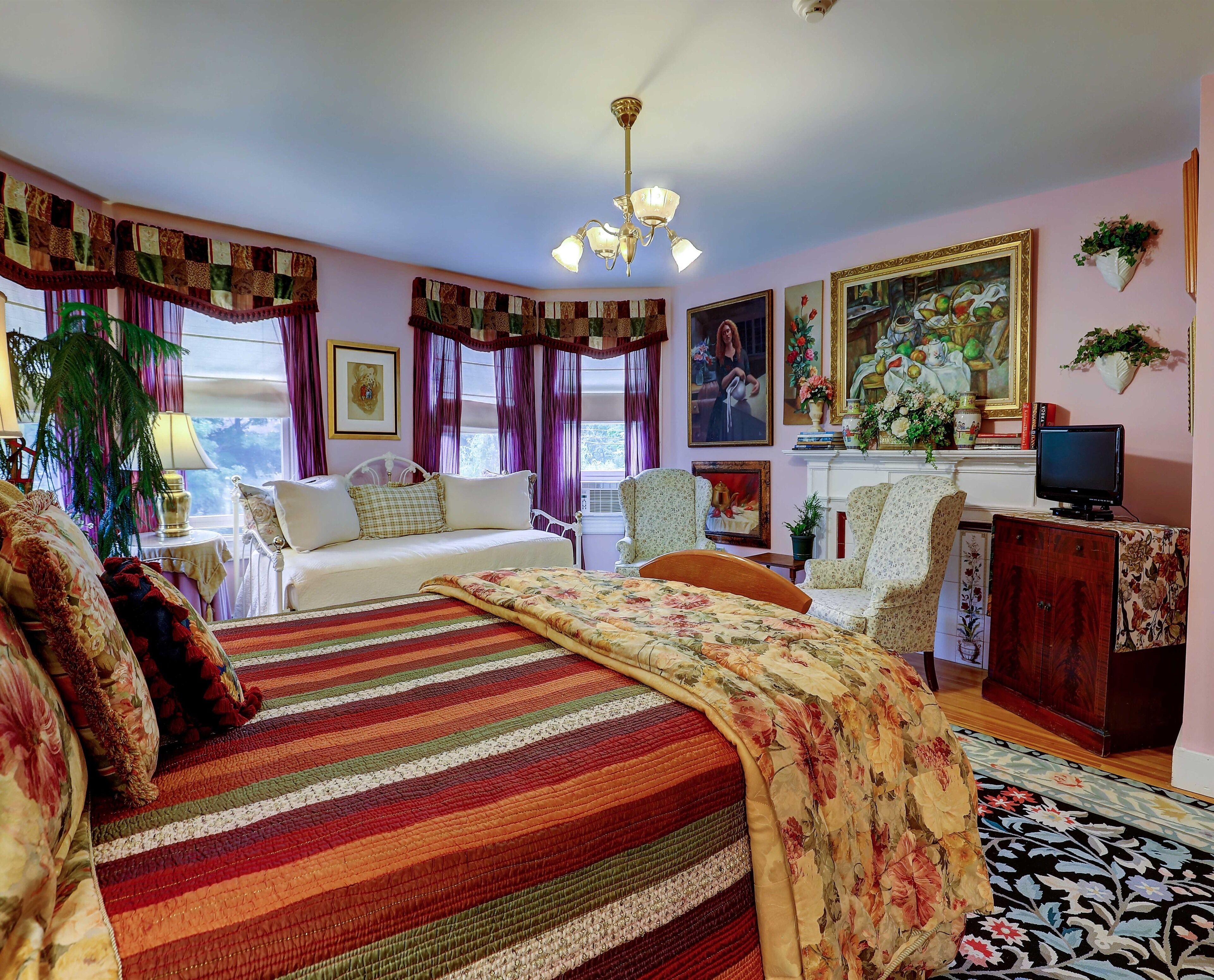 A bedroom with a large bed, a television, a fireplace, and various decorations.