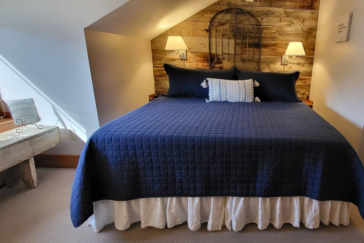 A bedroom with a large bed, two wall-mounted lamps, and a wooden headboard.
