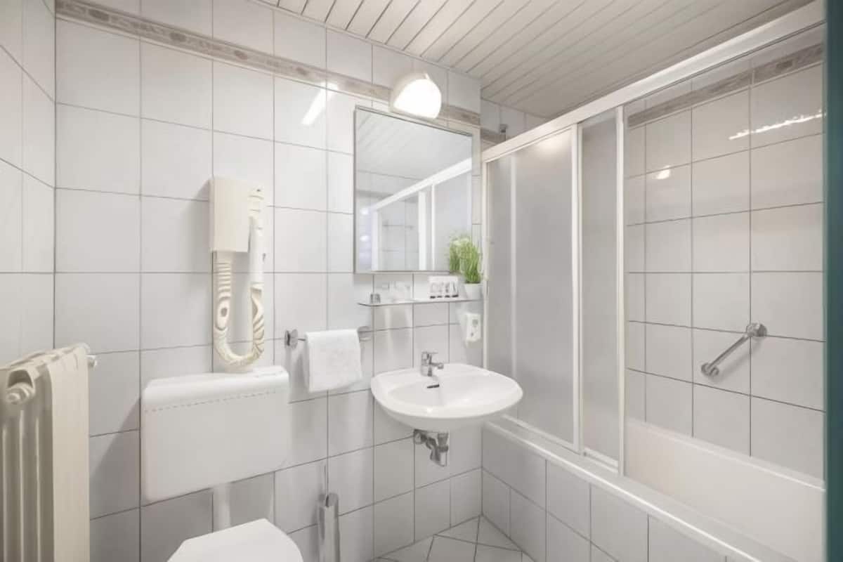 Une salle de bain équipée de toilettes, d’un lavabo, d’un miroir et d’une douche.