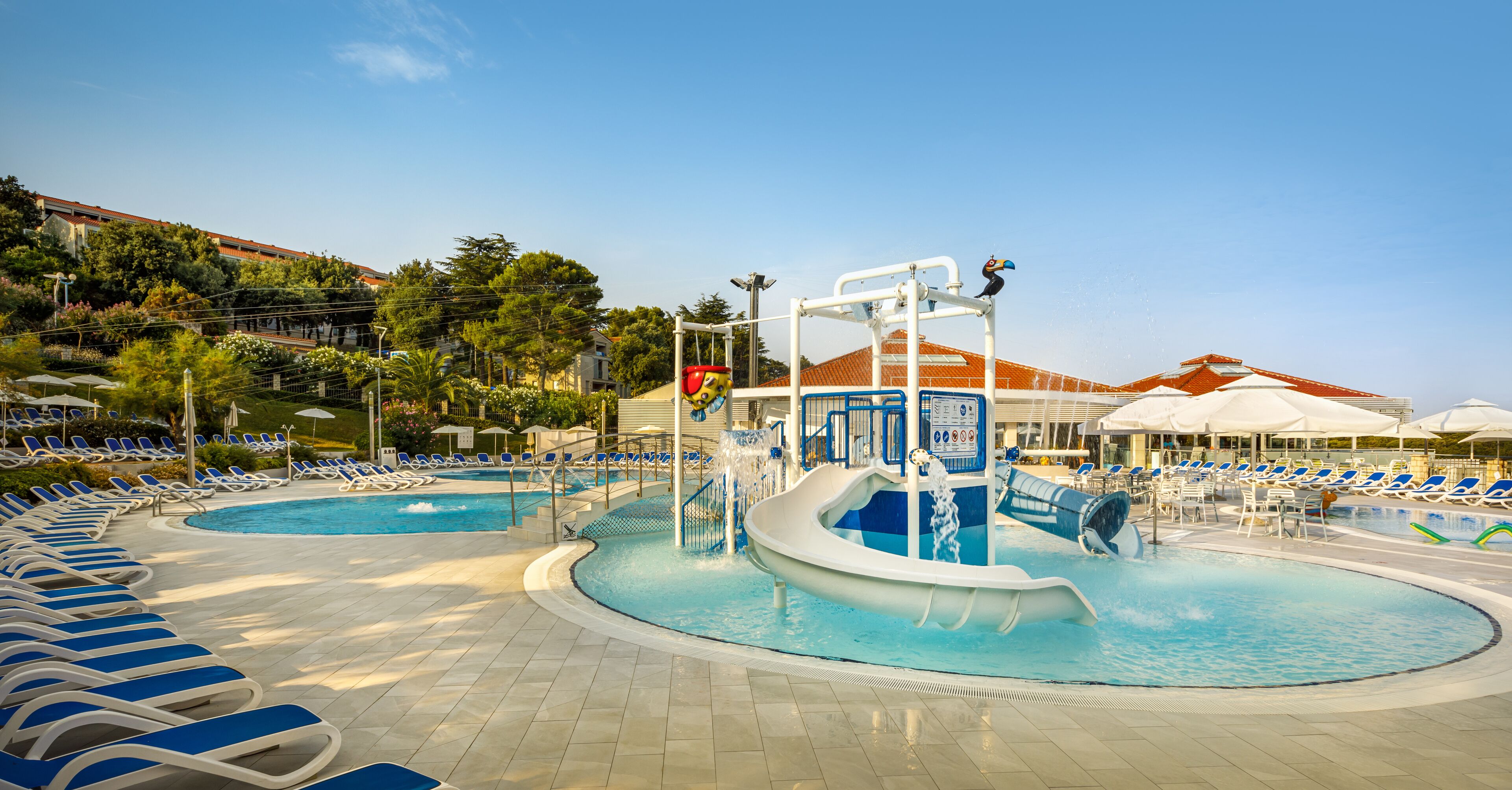 Un área de piscina con varias toboganes y sillas de descanso.