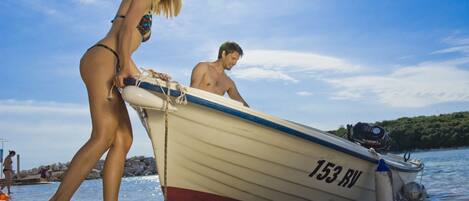 A boat with the number 153 RV on a rocky shore.