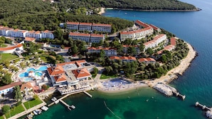 Vista aérea de un complejo turístico costero con varias edificaciones, una piscina y una zona de playa.