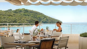 Comedor con mesas dispuestas para dos, con vistas panorámicas al litoral.