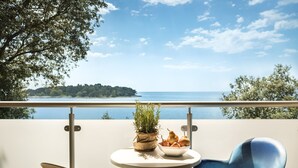 Un balcón con vista al mar, una mesa con una planta y un frutero, y dos sillas.