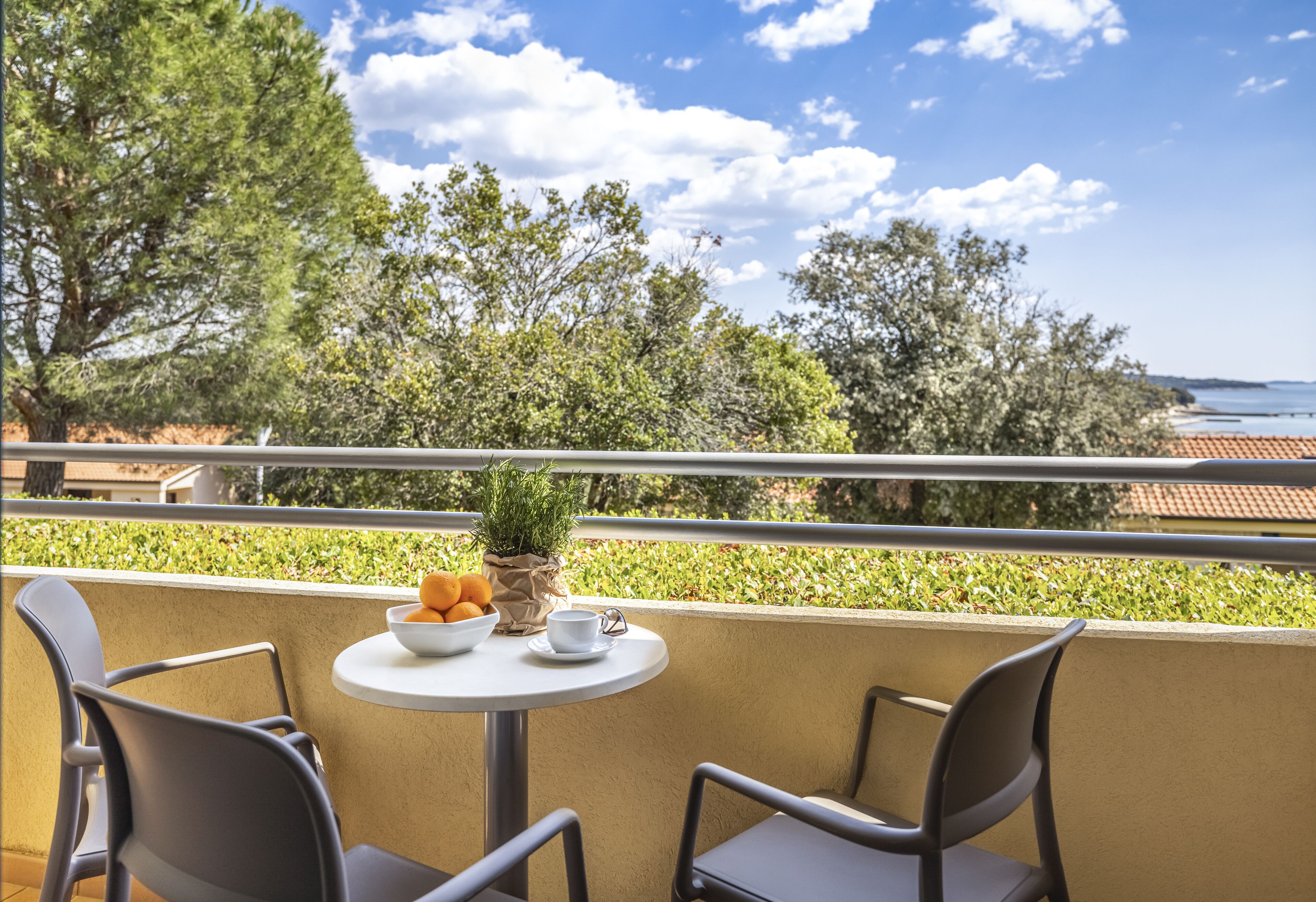 A balcony with two chairs, a small table, and a bowl of fruit.
