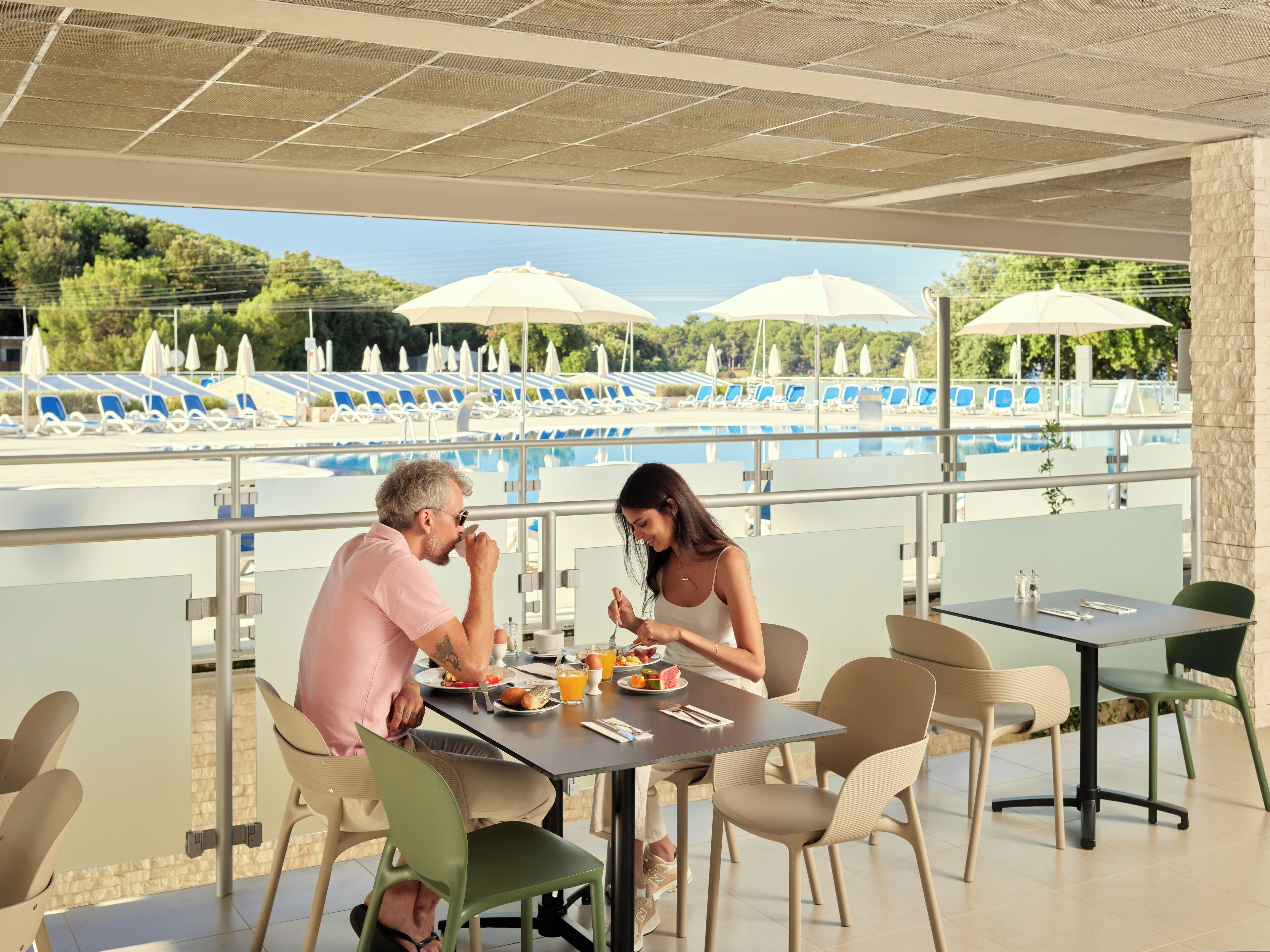 Comedor con vista a la piscina, mobiliario exterior y sombrillas.